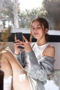 Jaunas žmogus naudojasi išmaniuoju telefonu ir naršo trumpus vaizdo įrašus, simbolizuojančius socialinių tinklų įtaką ir dėmesio koncentraciją.