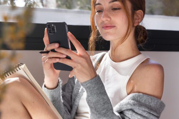 Kaip TikTok keičia mūsų kasdienybę ir psichiką Jaunas žmogus naudojasi išmaniuoju telefonu ir naršo trumpus vaizdo įrašus, simbolizuojančius socialinių tinklų įtaką ir dėmesio koncentraciją.