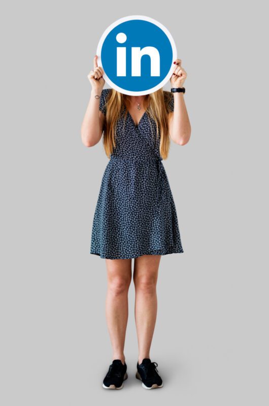 Profesionalas naudojantis patikrintą LinkedIn profilį kompiuteryje, akcentuojant skaitmeninius ryšius ir patikimumą.